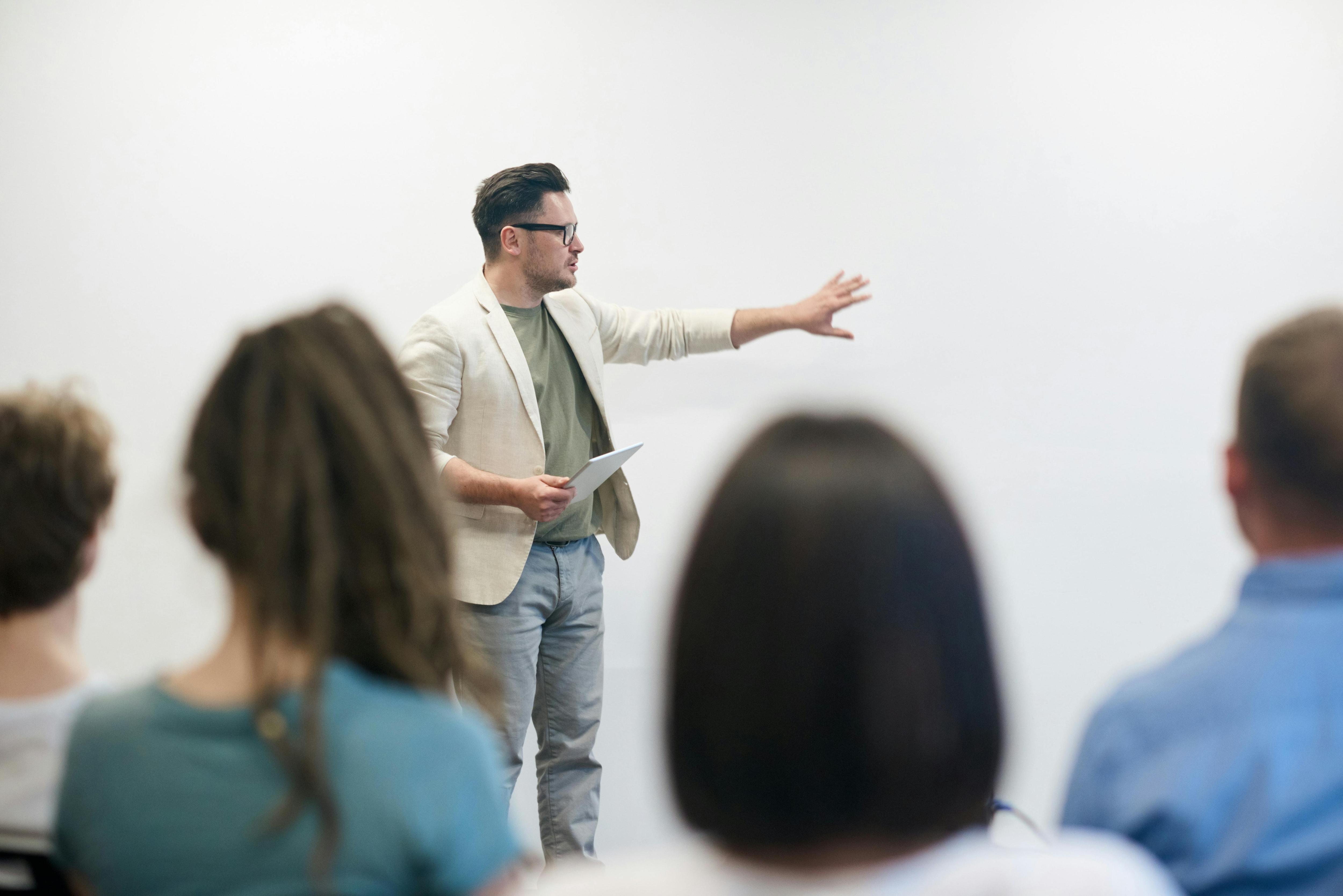 An image of a group of people overlooking a man talking to them