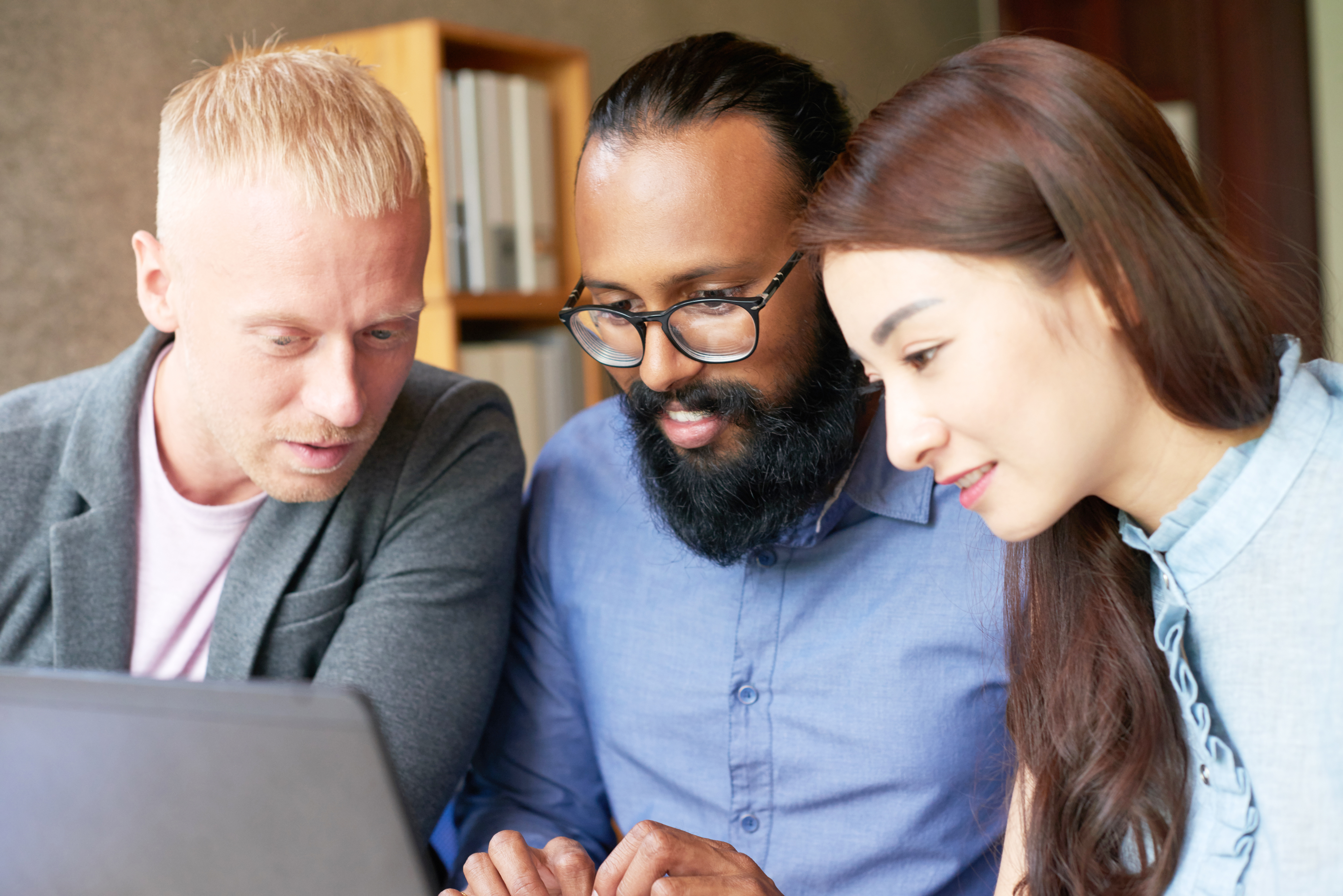 Three individuals seated in front of a laptop.