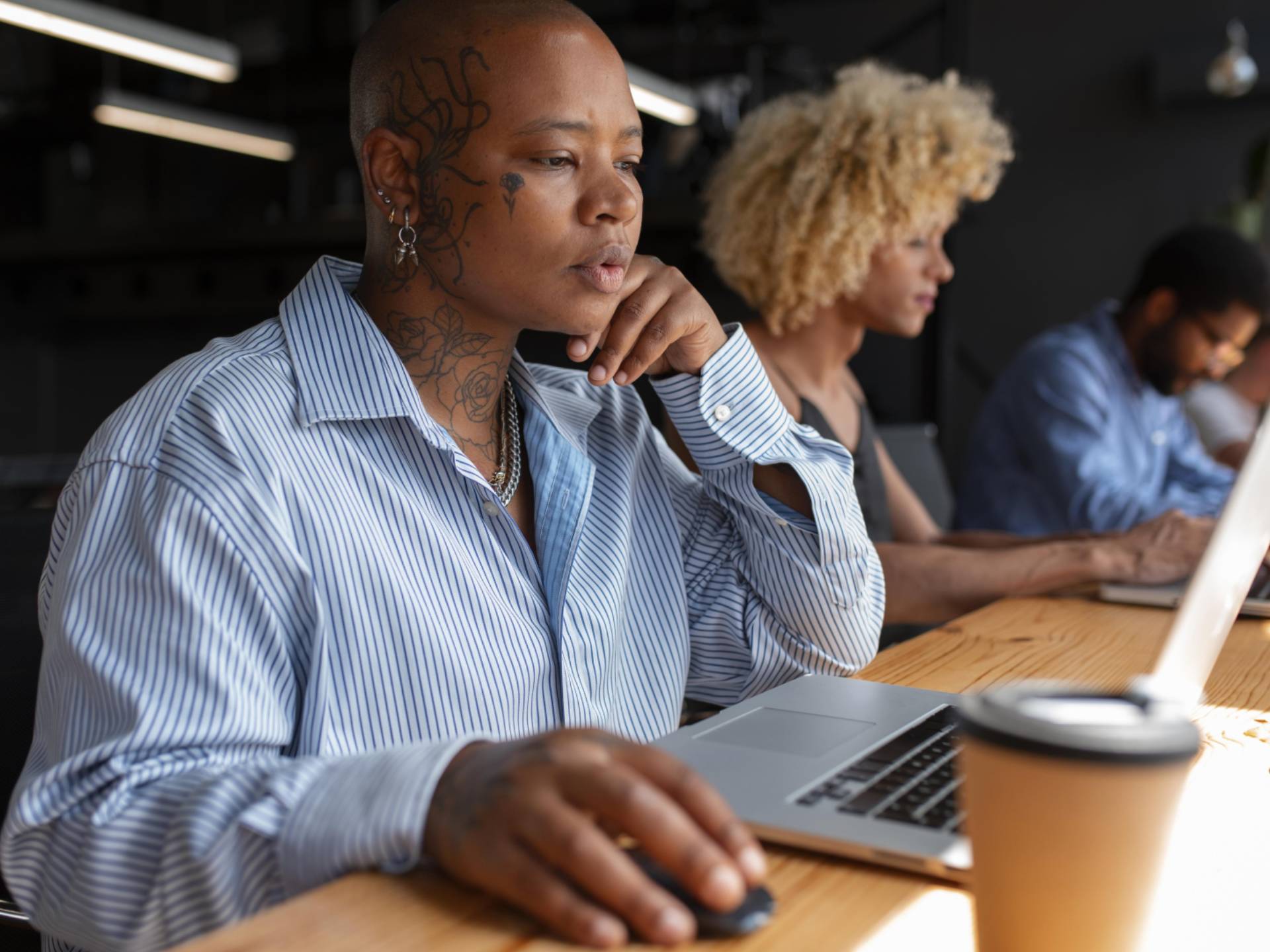 An image of a person sitting on a desk working on her laptop